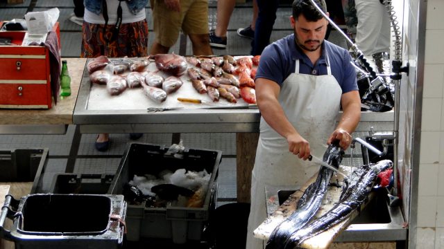 Mann säubert Degenfisch auf dem Markt in Funchal uf der Insel Madeira