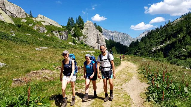 Drei Wanderer gehen im Sonnenschein im Piemont wandern